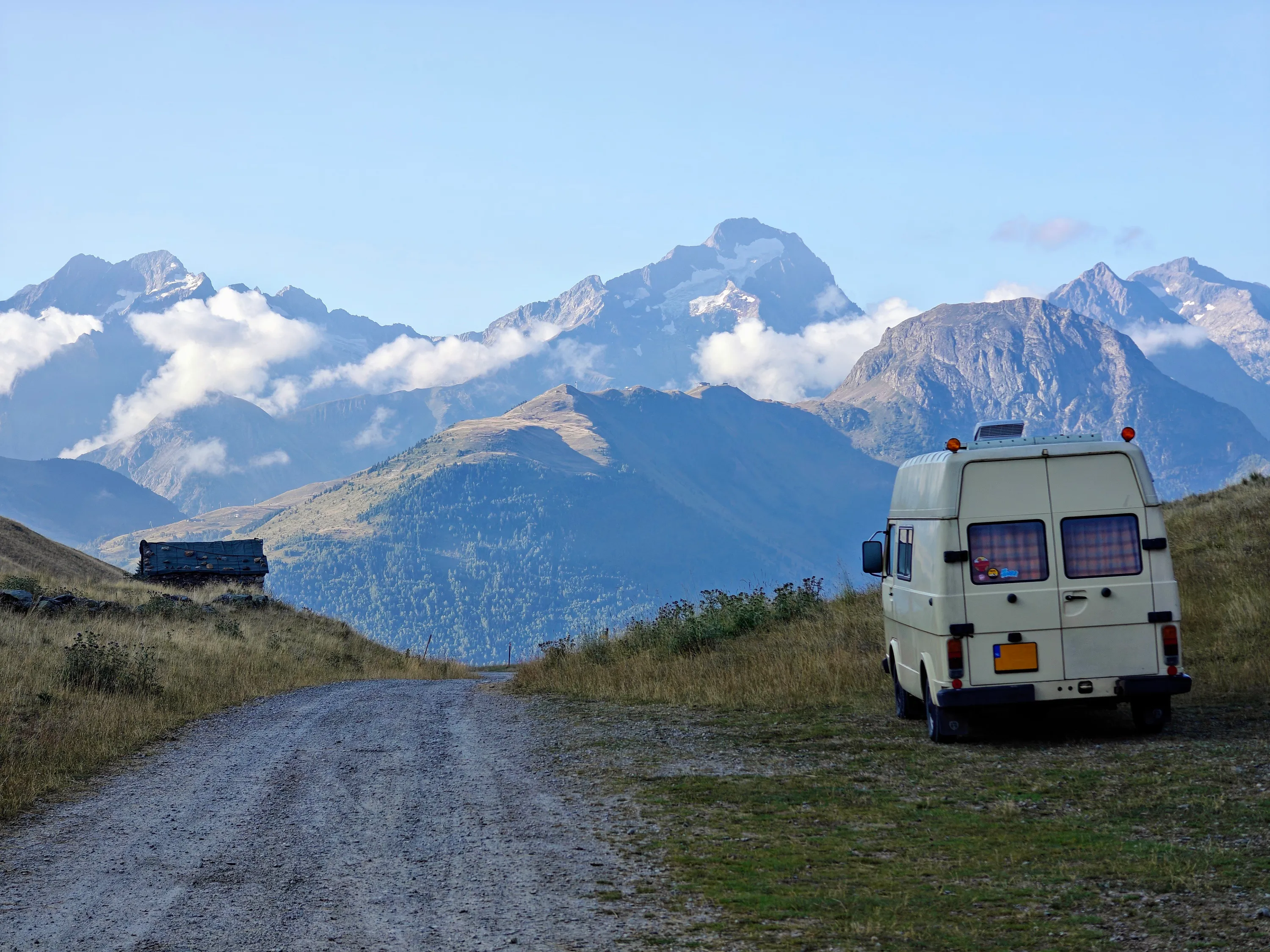 Bassie, mijn VW LT28 camper, geparkeerd op een bergpas in de Alpen met uitzicht op besneeuwde toppen