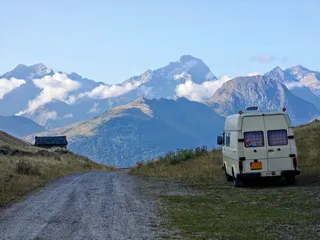 Bassie, mijn VW LT28 camper, geparkeerd op een bergpas in de Alpen met uitzicht op besneeuwde toppen