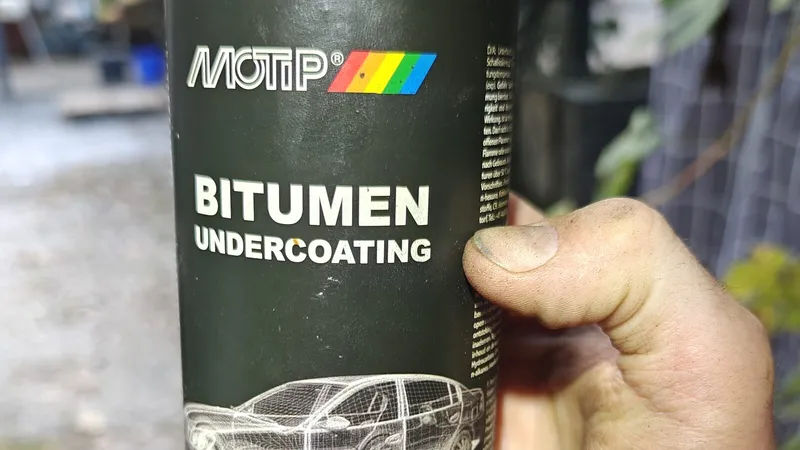 Een spuitbus MOTIP bitumen-undercoating in de hand