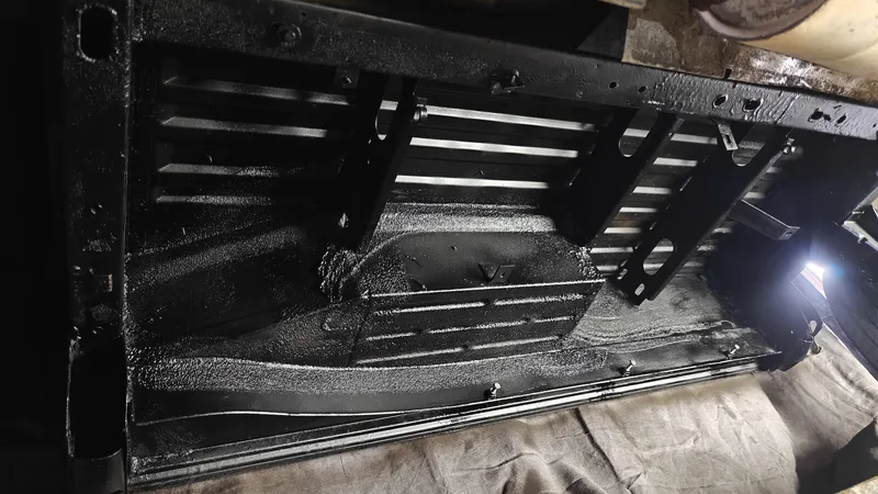 Close-up van de behandelde bodem waar de kachel komt, glanzend zwart met de beugels voor het frame